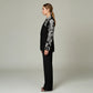 Model wearing Lavishly Me black longline blazer with intricate white floral beadwork on sleeves and lapel, side view