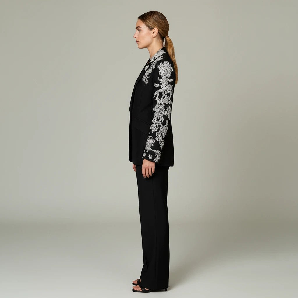 Model wearing Lavishly Me black longline blazer with intricate white floral beadwork on sleeves and lapel, side view