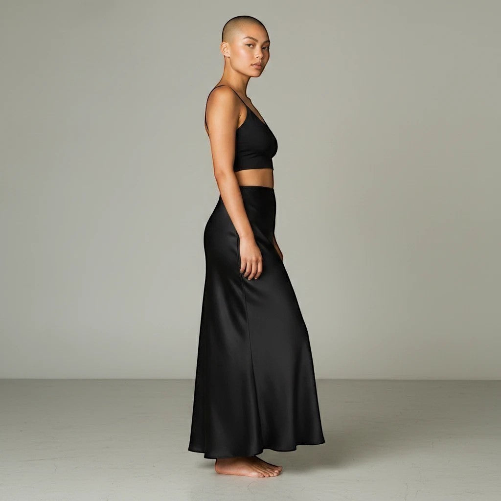 Model wearing a Lavishly Me black satin maxi skirt with a matching crop top in a minimalist studio setting.
