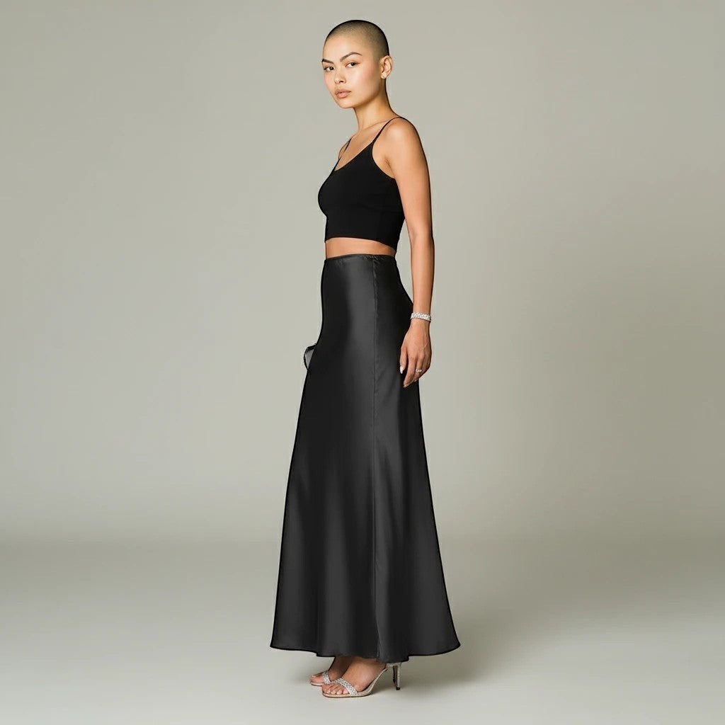 Model wearing a Lavishly Me black satin maxi skirt with a black crop top and heels, side view.