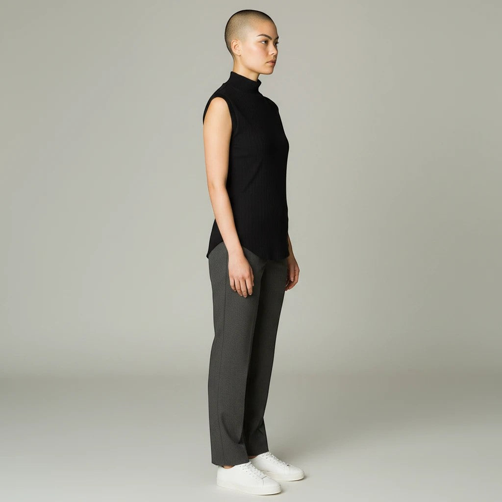 Model wearing a black Lavishly Me sleeveless turtleneck top with grey tailored trousers and white sneakers