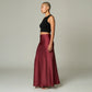 Model wearing a Lavishly Me burgundy satin maxi skirt with a black sleeveless crop top, side profile view.
