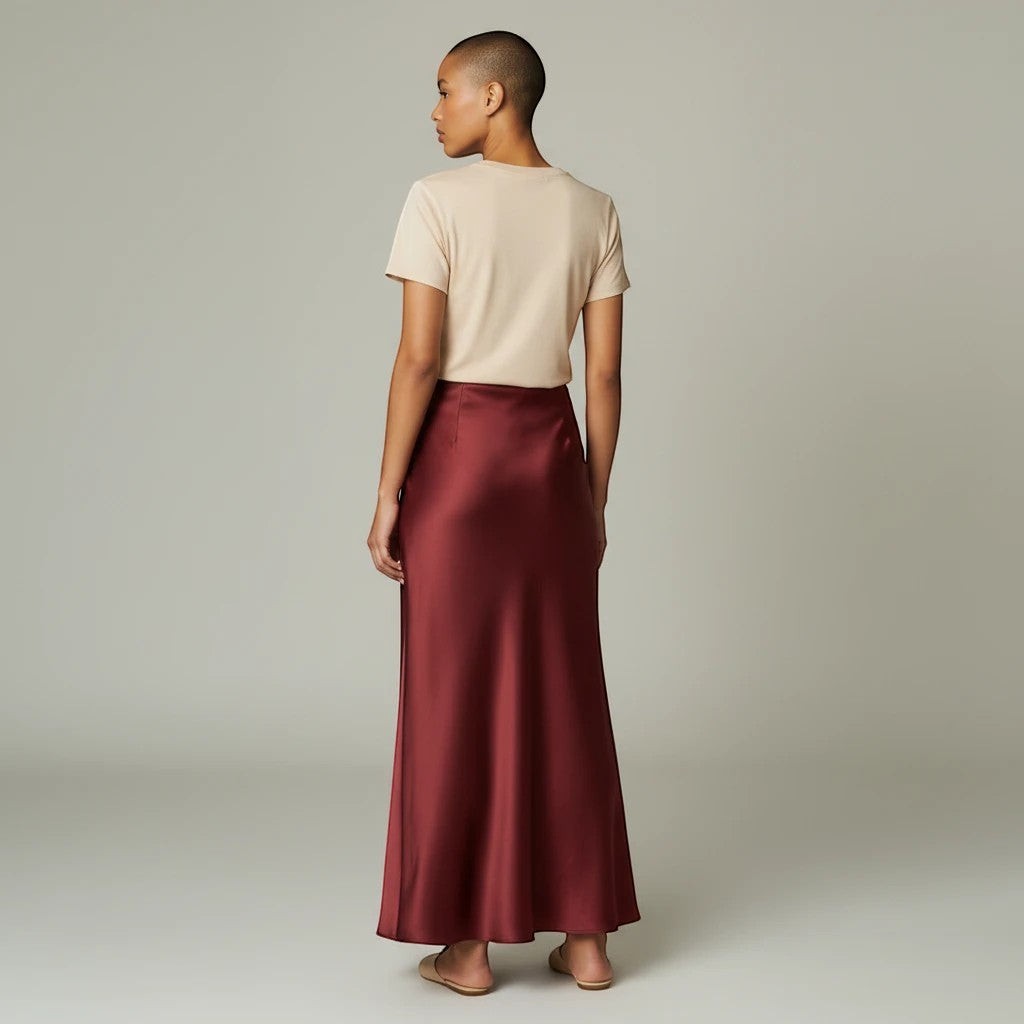 Model wearing a Lavishly Me burgundy satin maxi skirt with a beige t-shirt, viewed from the back.