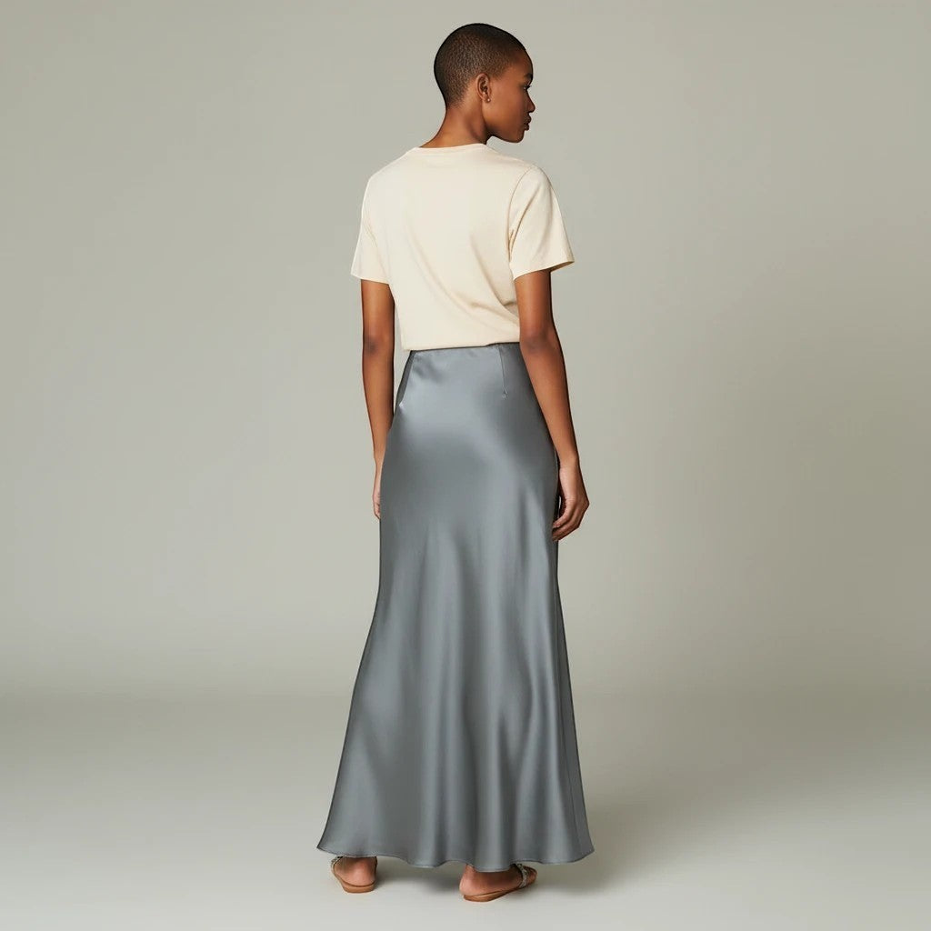 Model wearing a Lavishly Me grey satin maxi skirt with a beige t-shirt, viewed from the back.