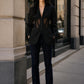Model wearing Lavishly Me black Nocturne mesh blazer with sheer corset-style panels and notched collar on city street