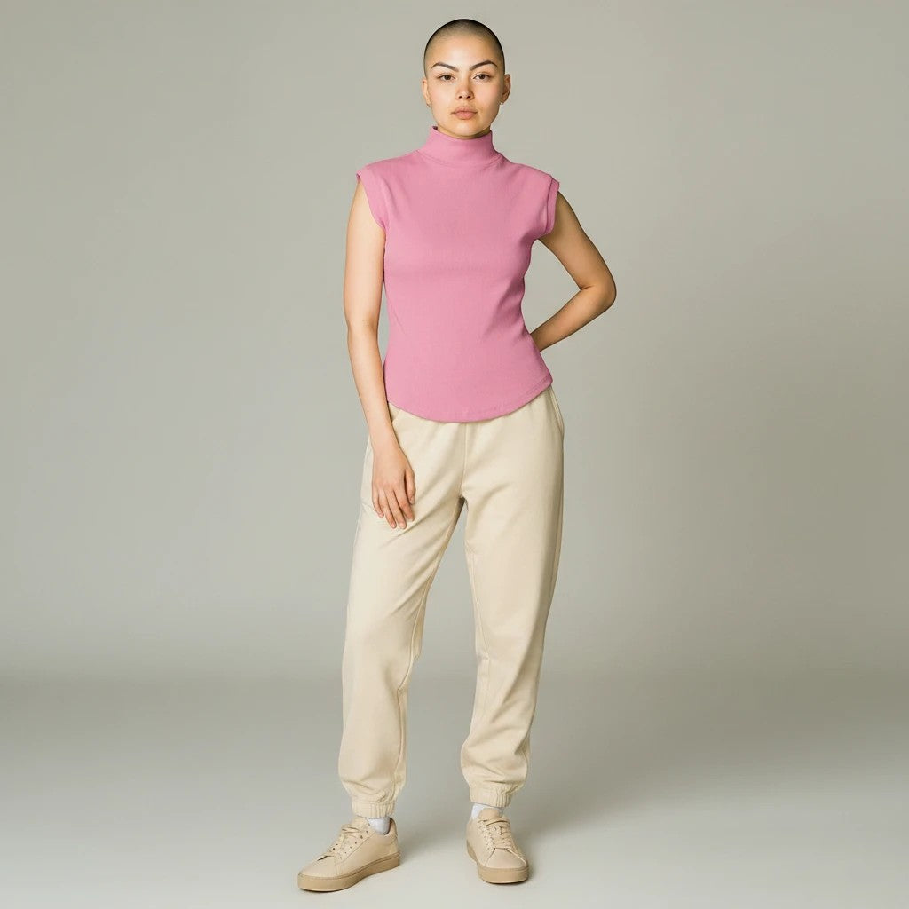 Model wearing a pink Lavishly Me sleeveless turtleneck top with beige joggers and sneakers
