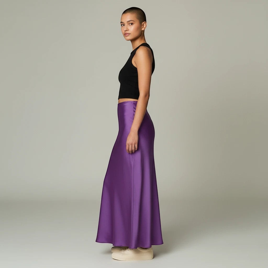 Model wearing a Lavishly Me purple satin maxi skirt with a black sleeveless crop top, side profile view.