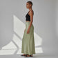 Model wearing a Lavishly Me sage green satin maxi skirt with a black tank top in a minimalist studio setting