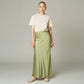 Model wearing a Lavishly Me sage green satin maxi skirt with a beige t-shirt and sneakers in a studio setting