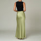Back view of a woman wearing a Lavishly Me sage green satin maxi skirt paired with a black sleeveless top.
