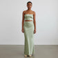 Model wearing a Lavishly Me sage green satin maxi skirt and matching strapless crop top in a minimalist studio setting.