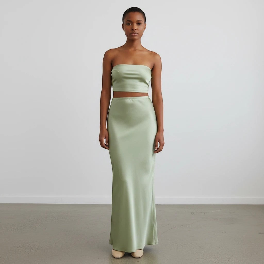 Model wearing a Lavishly Me sage green satin maxi skirt and matching strapless crop top in a minimalist studio setting.