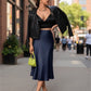 Lavishly Me Valencia satin fishtail skirt in navy blue worn by a woman with a black crop top and leather jacket