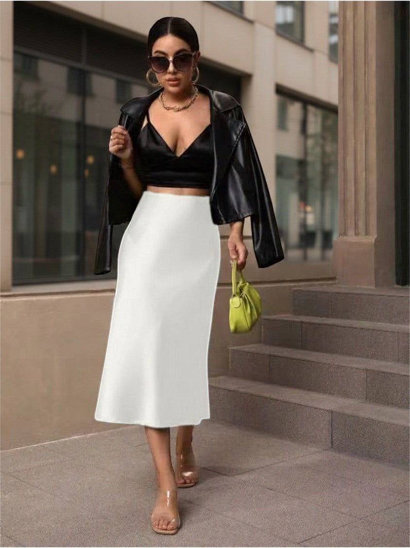 Lavishly Me white satin fishtail skirt worn by a woman with a black crop top and leather jacket on a city street.